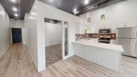 Located at 222 S Phillips Ave in downtown Sioux Falls, South Dakota, this single-floor unit blends industrial character with modern finishes throughout its thoughtfully designed layout. The kitchen serves as a central highlight, showcasing white shaker cabinetry that extends to impressive heights, complemented by a textured tile backsplash, light quartz countertops, stainless steel appliances, and a double-basin sink. Decorative pendant lighting hangs from exposed ductwork and a metallic ceiling, reinforcing the space's industrial aesthetic while adding a refined touch. Light wood-style flooring flows through the main living and kitchen areas, creating a warm contrast to the high ceilings and open framework above.

The bedroom area features plush carpet and a notable dual-closet configuration — one with a bifold door and another with a hinged door — each equipped with wire shelving systems for ample, organized storage. The bathroom is finished with large-format tile flooring, a white vanity with cabinetry, and a glass-enclosed walk-in shower adorned with marble-style wall tile and a built-in niche, delivering a clean, spa-like atmosphere. The overall design balances urban industrial elements with contemporary, polished details.