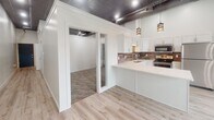 Located at 222 S Phillips Ave in downtown Sioux Falls, South Dakota, this single-floor unit blends industrial character with modern finishes throughout its thoughtfully designed layout. The kitchen serves as a central highlight, showcasing white shaker cabinetry that extends to impressive heights, complemented by a textured tile backsplash, light quartz countertops, stainless steel appliances, and a double-basin sink. Decorative pendant lighting hangs from exposed ductwork and a metallic ceiling, reinforcing the space's industrial aesthetic while adding a refined touch. Light wood-style flooring flows through the main living and kitchen areas, creating a warm contrast to the high ceilings and open framework above.

The bedroom area features plush carpet and a notable dual-closet configuration — one with a bifold door and another with a hinged door — each equipped with wire shelving systems for ample, organized storage. The bathroom is finished with large-format tile flooring, a white vanity with cabinetry, and a glass-enclosed walk-in shower adorned with marble-style wall tile and a built-in niche, delivering a clean, spa-like atmosphere. The overall design balances urban industrial elements with contemporary, polished details.