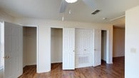 Located at 11200 Three Rivers Rd in Gulfport, Mississippi, this single-story property offers a straightforward and functional layout designed for comfortable everyday living. The interior features warm hardwood-style flooring that runs throughout, adding a sense of cohesion and character to the space. The textured ceilings lend a classic residential feel, while ceiling fans provide efficient air circulation. One of the standout features of this property is its generous storage capacity — the bedroom showcases multiple closets, including both open-rod closets and a set of double-door paneled closets, offering exceptional organization potential. A centrally positioned door between the closets provides access to additional utility or HVAC components, reflecting a thoughtful use of space. The neutral color palette of white walls and trim creates a clean, bright backdrop that can easily accommodate a variety of interior styles. Strategically placed HVAC vents throughout ensure year-round climate comfort. The overall ambiance is tidy, well-maintained, and move-in ready, making this Gulfport property a practical and inviting place to call home.
