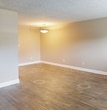 This 660-square-foot, one-bedroom, one-bathroom apartment on the fourth floor at 401 Rosery Rd NE in Largo, Florida offers a practical and well-appointed layout across a single floor. The living room is bright and open, featuring plush carpeting and a large sliding glass door that leads to a private balcony with views of mature surrounding trees, allowing abundant natural light to fill the space. The galley-style kitchen is efficiently designed with white shaker cabinetry, light marble-style countertops, a stainless steel sink, a stainless steel refrigerator, and additional appliances, all set above warm wood-look flooring that extends throughout the main areas. The 180-square-foot primary bedroom offers generous space with plush carpeting, mirrored sliding closet doors, and direct access to the bathroom. Additional rooms include a hallway, a utility room, and a dedicated closet for extra storage. The bathroom features a white vanity with a marble-style countertop, a tiled shower-tub combo with a curved curtain rod, and wood-look tile flooring. Neutral taupe walls and textured ceilings are consistent throughout, giving the apartment a cohesive and clean aesthetic.