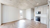 Located on the 14th floor at 333 Superior St in downtown Duluth, Minnesota, this three-bedroom, two-bathroom residence offers an industrial-modern aesthetic defined by exposed concrete ceilings, herringbone-patterned hardwood floors, and large windows that frame sweeping views of Lake Superior and the surrounding cityscape. The open kitchen and living area anchors the unit, featuring white cabinetry, subway tile backsplash, stainless steel appliances including a full-size refrigerator, dishwasher, and range, all set beneath the distinctive raw concrete ceiling with exposed pipework that adds to the loft-inspired character. Each of the three bedrooms is bright and airy, benefiting from generous windows that capture elevated views of the lake and Duluth's historic downtown neighborhoods. The primary bedroom provides a comfortable and well-proportioned retreat. Two bathrooms serve the unit, one featuring a sleek vanity with a white countertop and backlit mirror, while both continue the herringbone floor pattern for a cohesive look throughout. A well-organized hallway connects the private rooms and includes built-in shelving within a dedicated closet space. The unit's elevated position offers an abundance of natural light, and its clean, neutral palette creates a versatile and inviting living environment.