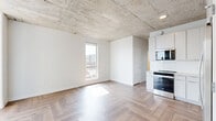 Located on the 14th floor at 333 Superior St in downtown Duluth, Minnesota, this three-bedroom, two-bathroom residence offers an industrial-modern aesthetic defined by exposed concrete ceilings, herringbone-patterned hardwood floors, and large windows that frame sweeping views of Lake Superior and the surrounding cityscape. The open kitchen and living area anchors the unit, featuring white cabinetry, subway tile backsplash, stainless steel appliances including a full-size refrigerator, dishwasher, and range, all set beneath the distinctive raw concrete ceiling with exposed pipework that adds to the loft-inspired character. Each of the three bedrooms is bright and airy, benefiting from generous windows that capture elevated views of the lake and Duluth's historic downtown neighborhoods. The primary bedroom provides a comfortable and well-proportioned retreat. Two bathrooms serve the unit, one featuring a sleek vanity with a white countertop and backlit mirror, while both continue the herringbone floor pattern for a cohesive look throughout. A well-organized hallway connects the private rooms and includes built-in shelving within a dedicated closet space. The unit's elevated position offers an abundance of natural light, and its clean, neutral palette creates a versatile and inviting living environment.