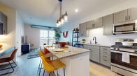 This single-floor residence offers a thoughtfully designed open-concept layout that seamlessly connects the kitchen, dining, and living areas. The kitchen is a standout feature, equipped with grey shaker-style cabinetry, granite countertops, a white subway tile backsplash, stainless steel appliances — including a gas range, microwave, and refrigerator — and a large central island with a granite surface and pendant lighting overhead. The island doubles as a dining and prep space, making it ideal for both everyday living and entertaining.

The living area is bright and welcoming, anchored by large sliding glass doors that open onto a private balcony, allowing abundant natural light and outdoor views to fill the room. Exposed ductwork adds an industrial design touch.

The bedroom is a calm retreat featuring large windows with expansive outdoor views, plush carpeting, and a ceiling fan. The bathroom is finished with grey shaker-style cabinetry, white countertops, and matte black hardware, consistent with the home's modern aesthetic. In-unit washer and dryer are conveniently located nearby. Light hardwood-style flooring flows throughout the main living areas, tying the whole space together with a clean, contemporary feel.