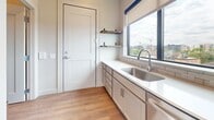 This efficiently designed 410-square-foot, one-bedroom, one-bathroom apartment offers a thoughtful layout across a single floor, maximizing every inch of available space. Warm hardwood-style flooring runs throughout, creating a cohesive and contemporary aesthetic.

The open-concept living area features a wall-mounted mini-split HVAC unit and a sliding glass door leading to a private balcony, where sweeping views of the water and city skyline can be enjoyed. Natural light pours in through large, black-framed windows, enhancing the airy feel of the space.

The galley-style kitchen is well-appointed with gray cabinetry, a subway tile backsplash, white countertops, and stainless steel appliances including a refrigerator, dishwasher, and range. Open floating shelves add functional storage near the entry. A dedicated laundry closet houses a stacked Whirlpool washer and dryer for added convenience.

The 170-square-foot primary bedroom benefits from a large window framing elevated city views, providing both natural light and a scenic backdrop. The bathroom features a gray vanity with ample drawer storage, a round mirror with a three-bulb vanity light, and clean, neutral finishes. This apartment delivers a modern, functional living experience with notable views and quality throughout.