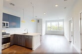 Located at 260 Avenue E in Bayonne, NJ, this well-appointed 2-bedroom, 2-bathroom residence offers a thoughtfully designed single-floor layout with a clean, modern aesthetic. The open-concept living, dining, and kitchen area serves as the heart of the home, featuring warm hardwood flooring, recessed lighting, and a large window that floods the space with natural light and outdoor views. The kitchen is a standout, boasting bold navy cabinetry, white subway tile backsplash, quartz countertops, a center island with pendant lighting, and a full suite of stainless steel appliances including a gas range, microwave, and refrigerator. The spacious primary bedroom offers generous proportions and a large picture window with scenic views of the surrounding neighborhood. The second bedroom also benefits from hardwood floors, a closet, and access to natural light. Both bedrooms are complemented by ample closet space, with a total of four closets throughout the unit. The two bathrooms are finished with marble-style tile flooring and clean white fixtures — one featuring a soaking tub with subway tile surround, the other a glass-enclosed walk-in shower. Additional conveniences include an in-unit laundry area and a utility room, completing this modern and functional Bayonne residence.