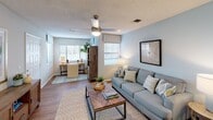This single-floor residence offers a thoughtfully designed layout that balances comfort and functionality across its key living areas. The living room serves as the heart of the home, featuring soft blue-gray walls, wood-look flooring, and a ceiling fan overhead. Natural light filters in through multiple windows dressed with Roman shades and blinds, creating a bright and welcoming atmosphere. The space extends into a flexible area that functions as a home office or additional seating zone, adding versatility to the floor plan.

The dining area is positioned conveniently off the main living space, highlighted by a pendant light fixture and warm wood-look flooring, offering an inviting setting for everyday meals. The kitchen features white shaker-style cabinetry, light countertops, and black appliances including a range, over-the-range microwave, and refrigerator.

Two carpeted bedrooms provide comfortable retreats, each with windows that bring in natural light. One bathroom offers a walk-in shower with white vanity cabinetry and wood-look flooring, while the second bathroom includes a shower-tub combination, matching white cabinetry, and coordinating finishes. Textured ceilings are consistent throughout the unit, contributing to the cohesive and clean aesthetic of this well-maintained residence.