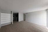 Located at 2900 South Gessner Road in Houston, TX, this one-bedroom, one-bathroom unit offers a well-organized, single-floor layout designed for comfortable everyday living. The open living room is bright and inviting, featuring plush carpeting, neutral gray walls, and large vertical blinds that allow natural light to filter through. A front entry door with an adjacent window adds to the airy feel of the space. Built-in shelving near the living area provides convenient display and storage options. The dining room sits adjacent to the kitchen, creating a seamless flow for entertaining. The kitchen features dark cabinetry, a functional countertop workspace, and access to a dedicated pantry for additional storage. An in-unit laundry area adds everyday convenience. The generously sized primary bedroom is carpeted and features a ceiling fan with light fixture, a window with blinds for natural light and privacy, and direct access to a spacious walk-in closet outfitted with multiple shelving and hanging rods. The bathroom includes a wide vanity with an integrated sink, ample under-sink cabinetry, a lighted mirror, and a hallway connection that links the private areas of the home. Ceiling fans throughout and consistent neutral tones give the unit a clean, functional ambiance.