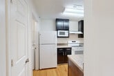 Located at 6337 Village Center Dr in Bealeton, VA, this single-floor, three-bedroom, two-bathroom home offers a well-organized layout with a comfortable and functional design throughout. The galley-style kitchen is a standout feature, lined with rich dark cabinetry contrasted by granite-style countertops and light hardwood flooring. It is fully equipped with a full-size refrigerator, electric range, built-in microwave, and dishwasher, with a separate pantry providing additional storage. The kitchen flows conveniently toward a dedicated laundry room housing a full-size washer and dryer. The combined dining and living area is generously sized, featuring plush carpeting and French doors that open to a private balcony, filling the space with natural light and outdoor views. Each of the three bedrooms continues the carpeted aesthetic and is served by ample closet space — with five closets distributed throughout the home. The primary bedroom offers a comfortable footprint with good natural light. Both bathrooms feature hardwood-style flooring, dark vanity cabinetry with granite-style countertops, and tub/shower combinations. A welcoming entrance completes this thoughtfully arranged home, making it a practical and inviting residence in the Village Center community.
