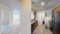 Located at 3109 Grace Park Dr in Morrisville, NC, this single-floor, 2-bedroom, 2-bathroom residence offers a well-organized layout across a comfortable footprint. The kitchen is outfitted with warm-toned wood cabinetry, dark granite-style countertops, tile flooring, a black electric range with overhead ventilation, and a double sink with pendant lighting. A structural column separates the kitchen from the adjacent living area, which features plush carpeting and a ceiling fan, with natural light streaming in through large windows fitted with horizontal blinds. Both bedrooms are finished with soft carpeting, neutral-toned walls, and ceiling fans. The primary bedroom is generously sized and includes access to a walk-in closet with multi-level wire shelving for organized storage. The secondary bedroom also benefits from a window with natural light. The full bathroom includes a wood vanity with granite-style countertops, a full-width mirror, and a soaking tub with a shower combo and grab bars. The second bathroom features a classic pedestal sink and tile flooring. A dedicated laundry area accommodates full-sized washer and dryer units. Throughout, the space maintains a clean, neutral palette suited for a variety of furnishing styles.