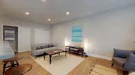 This single-floor residence offers a thoughtfully designed layout with a cohesive, neutral color palette of soft grays and warm whites throughout. The living area is a welcoming space finished with light hardwood flooring, recessed ceiling lighting, and ample room for comfortable seating. A vibrant teal abstract artwork adds a pop of color to the walls, complemented by a reading nook with a window that brings in natural light. Double closet doors provide convenient storage directly off the living space.

The galley-style kitchen is well-equipped with stainless steel appliances, including a range, microwave, refrigerator, and dishwasher, all set against crisp white shaker cabinetry and dark countertops with a white subway tile backsplash. Hardwood flooring extends seamlessly into the adjacent dining area, where large sliding glass doors flood the space with natural light and offer views of the outdoors.

The bedrooms are comfortably sized, each featuring ceiling fans, carpeted floors, and closet storage. Natural light filters in through slatted blinds, creating a restful atmosphere. The primary bathroom offers a sleek walk-in glass shower with tile surround and a clean white vanity, while the secondary bathroom features a full tub-shower combo with marble-style tile and a modern vanity.