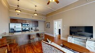 Located at 610 Mulberry St in historic downtown Macon, Georgia, this one-bedroom, one-bathroom unit showcases a thoughtful blend of classic architectural character and modern finishes. Throughout the space, rich hardwood floors and notably high ceilings with crown molding create an open, airy atmosphere, while ceiling fans provide year-round comfort.

The open-concept living and kitchen area forms the heart of the unit. The kitchen is well-appointed with dark wood cabinetry, stainless steel appliances including a gas range, microwave, dishwasher, and refrigerator, all complemented by granite countertops. A large granite-topped breakfast bar with seating separates the kitchen from the living area, making it ideal for casual dining or entertaining. The living room benefits from a bank of windows that invite natural light and offer views of the surroundings.

The spacious primary bedroom features hardwood floors, high ceilings with crown molding, a ceiling fan, and windows dressed with blinds and drapes. A dedicated closet with built-in shelving and hanging rod provides practical storage.

The bathroom is finished with tile flooring, a granite-topped vanity with dark wood cabinetry, a glass-enclosed shower, and the added convenience of a stacked washer and dryer unit within the space.