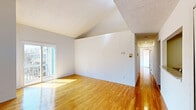 Located at 2100 Hana Road in Edison, NJ, this multi-level residence offers two bedrooms, three bathrooms, and a versatile loft spread across three floors. Warm hardwood flooring flows throughout the main living areas, complementing the bright, clean aesthetic of the space. The main floor centers around an open living area with soaring vaulted ceilings that lend a dramatic sense of height and openness, with a pass-through window connecting it to the galley-style kitchen. The kitchen is well-appointed with rich dark wood cabinetry, granite countertops, and black appliances, including a gas range. Each of the three bathrooms features dark wood vanities with white countertops and tile flooring, with one bathroom including a walk-in shower. The generously sized primary bedroom benefits from natural light and includes access to ample closet space, while the second bedroom features dual windows and hardwood floors. The upper loft level, reached by staircase, provides flexible additional living space with vaulted ceilings and a window. A balcony, dedicated laundry area, and six closets — including a spacious walk-in — round out the practical amenities. The multi-level layout and architectural details make this an efficient and characterful home.