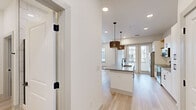 Located at 301 W Ninth St in Dallas, TX, this single-story unit offers a thoughtfully designed interior with contemporary finishes throughout. Light wood-tone flooring runs continuously across the space, creating a cohesive and airy feel complemented by crisp white walls and recessed lighting.

The kitchen serves as a central highlight, featuring white shaker-style cabinetry with dark hardware, stainless steel appliances including a range and over-the-range microwave, and a generous island with a quartz countertop and undermount sink. Decorative woven pendant lights add warmth above the island, while French doors at the rear of the kitchen bring in natural light and provide outdoor access.

The bathroom showcases a bold design aesthetic, with a striking black-and-white geometric accent wall, a gold-framed round mirror, white vanity cabinetry with marble-look countertops, and matte black fixtures. Conveniently adjacent is an in-unit laundry area.

The walk-in closet offers ample storage with wrap-around hanging rods and shelving. Additional rooms provide flexible living spaces, including one with built-in wall shelving and another with dual windows that invite natural light. The overall design balances modern style with practical functionality throughout.