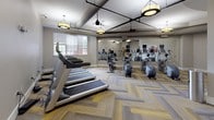 The fitness center at 430 Allied Pl in Gaithersburg, Maryland is a well-appointed, single-floor exercise facility designed to support a complete workout routine. The space features a distinctive herringbone-patterned carpet flooring in warm tones of gold, gray, and tan, lending a polished yet inviting aesthetic throughout.

The cardio area is equipped with multiple treadmills, each fitted with individual display screens, neatly arranged along one wall and positioned near windows with natural light filtering through slatted blinds. Adjacent to the treadmills, a selection of elliptical trainers, stationary bikes, and rowing-style machines provides a diverse range of low-impact cardiovascular options.

A large floor-to-ceiling mirror along one wall visually expands the space and allows users to monitor their form during exercise. Exposed ductwork and black pipe accents along the ceiling contribute an industrial design element, balanced by elegant pendant light fixtures with warm-toned shades that illuminate the room evenly.

Vaulted ceiling sections add architectural interest and a sense of openness to portions of the room. Artwork adorns the walls, adding a touch of color and character. The space is completed with ceiling fans for air circulation and access to an adjacent room, making this fitness center a functional and thoughtfully designed amenity.