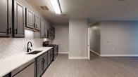 Located at 333 State Street in Bridgeport, Connecticut, this single-floor residential unit presents a thoughtfully designed interior with a cohesive modern aesthetic. The space features consistent light gray wood-look flooring throughout the main areas, complemented by clean white baseboards and neutral gray walls that create a calm, contemporary atmosphere.

The kitchen stands out as a focal point, outfitted with gray shaker-style cabinetry accented by matte black hardware, white quartz countertops, and a striking herringbone tile backsplash. Stainless steel appliances — including a refrigerator, range, microwave, and dishwasher — complete this well-appointed cooking space.

A central hallway connects the various rooms, providing a logical and efficient flow through the unit. The living and bedroom areas are generously proportioned, with large windows that invite natural light and offer views of the surrounding Bridgeport streetscape. The bedrooms feature darker wood-tone flooring, adding warmth and visual contrast to the lighter common areas.

The bathrooms maintain the unit's clean design language, featuring white tile surrounds on the soaking tubs and bright, minimal fixtures with brushed nickel accents. Overall, the unit presents a move-in-ready, well-finished living environment in a convenient downtown Bridgeport location.