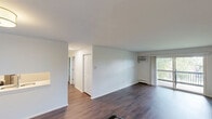 Located at 1049 S Main St in Crown Point, Indiana, this 2-bedroom, 2-bathroom unit offers a well-organized single-floor layout designed for comfortable everyday living. The living room is a highlight of the space, featuring rich dark hardwood flooring, a wall-mounted air conditioning unit, and a sliding glass door that opens to a private balcony with an outdoor railing — bringing in abundant natural light and views of surrounding greenery. An interior pass-through window connects the living area to the kitchen, adding an open, communicative feel between spaces. Both bedrooms are carpeted and generously proportioned, each offering windows with natural light and baseboard heating. The primary bedroom also includes a wall-mounted air conditioning unit for added climate control. The two bathrooms are thoughtfully updated: one features a clean, modern vanity with a speckled quartz countertop, an undermount sink, and elegant pendant lighting above a large mirror, while the second showcases a classic subway tile tub surround with a built-in niche and brushed hardware. Additional features include a dedicated closet, a connecting hallway, and durable dark hardwood flooring in the main living areas. The overall aesthetic is clean and neutral, offering a move-in ready canvas throughout.