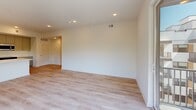 This thoughtfully designed two-bedroom, one-bathroom residence in Bala Cynwyd, PA offers a clean, modern aesthetic throughout. Light-toned hardwood flooring flows seamlessly across the entire living space, complementing the crisp white walls and recessed lighting that give every room a bright, airy feel.

The open-concept kitchen and living area serves as the heart of the home. The kitchen is outfitted with sleek gray flat-panel cabinetry, stainless steel appliances including a French door refrigerator, gas range, and built-in microwave, along with a white quartz waterfall island and subway tile backsplash. A modern linear pendant light adds a refined finishing touch. The living area is generously proportioned and opens directly onto a private balcony through floor-to-ceiling sliding glass doors, offering sweeping views of the tree-lined Bala Cynwyd neighborhood below.

The spacious primary bedroom receives abundant natural light through large windows and features a double-door closet. The second bedroom is equally well-lit with a wide window framing outdoor greenery. The bathroom is elegantly appointed with large-format beige tile in a walk-in glass-enclosed shower, mosaic tile flooring, and clean white fixtures. The hallway includes a louvered-door closet for additional storage. The building's contemporary exterior features balconies and modern paneling.