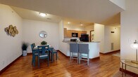 Located at 430 Silver Maple Ridge in Charleston, WV, this single-floor residence offers a well-organized layout with a cohesive design throughout. The open-concept kitchen and dining area form the heart of the home, where warm hardwood-style flooring flows seamlessly between spaces. The kitchen is outfitted with light maple cabinetry, granite countertops, a breakfast bar with seating, and a full suite of black appliances including a range, microwave, dishwasher, and refrigerator. The adjacent dining area provides comfortable space for a full table and bench seating. The living room features plush carpeting, a door with direct outdoor access, and a window that brings in natural light and exterior views. Two bedrooms, each carpeted and thoughtfully proportioned, offer a quiet retreat — one with a large window overlooking greenery. The full bathroom includes a warm-toned vanity with ample cabinet storage, tile flooring, and a shower-tub combination. A dedicated laundry room houses a full-size washer and dryer alongside the water heater and electrical panel, all set on durable tile flooring. Rich wood trim and interior doors add warmth and consistency throughout the entire residence.