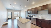 Located at 15329 Monument Ridge Court in Colorado Springs, CO, this well-appointed two-bedroom, three-bathroom single-story home offers a thoughtfully designed layout across a comfortable footprint. The kitchen serves as the heart of the home, featuring rich dark cabinetry, granite countertops, a tile backsplash, a central island, and a full suite of stainless steel appliances including a refrigerator, range, microwave, and dishwasher. Wood-style plank flooring runs throughout the main living and kitchen areas, lending warmth and continuity to the space. The living area is bright and open, with access to an outdoor balcony and windows that frame scenic views of the surrounding Colorado landscape. The primary bedroom is generously sized, appointed with plush carpeting, a ceiling fan, and a walk-in closet outfitted with wire shelving. The second bedroom is equally comfortable, also featuring carpeted flooring, a ceiling fan, and its own closet with built-in storage. The bathrooms are finished with granite-topped dark wood vanities, wood-style flooring, and clean white tile surrounds in the tub and shower areas. A dedicated half bath provides added convenience. The home's neutral color palette and modern finishes create a clean, move-in-ready aesthetic throughout.