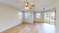 This single-floor, 2-bedroom, 2-bathroom residence offers a practical and comfortable layout designed for everyday living. Light-toned wood-style flooring runs consistently throughout the space, lending a cohesive and clean aesthetic to every room.

The open living area is bright and inviting, featuring multiple windows with blinds that allow generous natural light to fill the room. A ceiling fan with integrated lighting provides both air circulation and illumination, while a textured ceiling adds a classic finishing touch. A sliding door connects the living area to the outdoors, further enhancing the sense of openness.

The kitchen is well-equipped, showcasing light wood cabinetry paired with dark granite-style countertops and a mosaic tile backsplash. Black appliances—including a range, microwave, dishwasher, and refrigerator—complete the functional cooking space, which also benefits from a window above the sink.

The primary bedroom is generously sized, fitted with its own ceiling fan and windows that invite natural light. A dedicated closet with louvered doors provides ample storage. The second bedroom mirrors this comfortable design.

Both bathrooms are efficiently laid out, each featuring a vanity with wood cabinetry and dark countertops, a tub-shower combination with tiled surround accented by warm-toned tiles, and wood-style flooring. An additional closet in the common area offers extra storage convenience throughout the home.