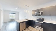 Located at 98 Washington Ave in Belleville, NJ, this thoughtfully designed one-bedroom, one-bathroom residence offers a well-organized single-floor layout with a generous overall footprint. Light gray luxury vinyl plank flooring runs throughout, creating a cohesive and modern aesthetic.

The kitchen is a standout feature, boasting a large waterfall-edge quartz island with an undermount sink and sleek pendant lighting overhead. Two-tone cabinetry — dark lower cabinets paired with gray uppers — is complemented by a light mosaic tile backsplash and a full suite of stainless steel appliances, including a refrigerator, electric range, and microwave.

The open living area flows naturally from the kitchen, providing a bright and flexible space bathed in recessed lighting. Crisp white walls enhance the airy feel throughout.

The bedroom is a comfortable retreat, featuring a window with views of surrounding greenery, a built-in PTAC unit for climate control, and a double-door closet for storage. An additional dedicated closet with rod and shelf further maximizes organization.

The bathroom is finished with floor-to-ceiling light tile surround and a soaking tub with chrome fixtures, offering a clean and calming environment. The overall design of the residence reflects a contemporary sensibility with practical, high-quality finishes throughout.