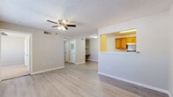 Located at 5325 N Oak St in Springdale, Arkansas, this single-story, three-bedroom, two-bathroom home offers a functional and comfortable layout. The open living room is finished with light wood-style flooring, a textured ceiling, and a ceiling fan with integrated lighting. A half-wall partition connects the living area to the kitchen, which features warm oak cabinetry, white countertops, a stainless steel range, and a built-in range hood — all set beneath a textured ceiling with overhead lighting. Built-in shelving adds practical storage along the hallway leading to the bedrooms. The three bedrooms are carpeted in neutral tones and receive natural light through slatted blinds. The spacious primary bedroom includes a ceiling fan and multiple door access points. The primary bathroom offers a lengthy dual-sink oak vanity with white countertops and light wood-style flooring, alongside a bathtub. The second bathroom mirrors a similar design with a single-sink vanity and a tub-shower combination. A dedicated laundry area houses a Whirlpool washer with overhead wire shelving and hookups for a dryer. Clean neutral walls, consistent flooring, and a practical floor plan define the overall character of this well-organized home.