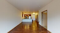 Located at 3261 SW Avalon Way in Seattle's West Seattle neighborhood, Unit 206 is a thoughtfully designed single-floor residence that blends modern finishes with a functional open-concept layout. Rich hardwood flooring flows throughout the main living areas, anchoring the space with warmth and continuity.

The kitchen serves as a central hub of the home, featuring a spacious island with a built-in sink, stainless steel appliances including a refrigerator, range, and microwave, and rich wood cabinetry complemented by open floating shelves. Pendant lighting above the island adds a stylish, contemporary touch. The kitchen opens seamlessly into the living area, which is bathed in natural light through a large picture window offering leafy outdoor views.

The bedroom is a quiet retreat, featuring plush carpeting and a tall window that frames greenery outside, creating a serene atmosphere. The bathroom is clean and efficiently laid out, with wood cabinetry, a wide vanity with an undermount sink, and hardwood-style flooring that maintains design cohesion with the rest of the unit.

The overall ambiance of the space is bright, modern, and inviting, with a neutral color palette that highlights the quality of the finishes. The efficient floor plan makes excellent use of space, creating a comfortable and functional home in the heart of Seattle.