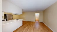 Located at 12345 Old Pomerado Road in Poway, CA, this one-bedroom, one-bathroom unit offers a well-organized single-level layout. Light wood flooring runs consistently throughout the entire space, creating a warm, cohesive aesthetic. The open-concept kitchen and living area form the heart of the unit. The kitchen is outfitted with white shaker-style cabinetry, white quartz countertops, a stainless steel refrigerator, electric range, built-in microwave, and dishwasher. A ceiling fan with integrated lighting fixture adds comfort to the dining area adjacent to the kitchen. The living room is bright and open, featuring warm beige walls and generous wall space for flexible furniture arrangements. The bedroom offers a comfortable footprint with a large window that brings in natural light and views of the surrounding exterior. A wall-mounted air conditioning unit provides climate control. The bathroom is well-appointed with wood-look flooring, white cabinetry with brushed nickel hardware, a white countertop vanity, and a full shower-tub combination enclosed by sliding glass doors, topped with a high clerestory window for natural light.