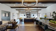 This single-floor community clubhouse is designed with a sophisticated yet welcoming aesthetic, blending contemporary and transitional design elements throughout its well-defined zones. The centerpiece of the space is an expansive open lounge anchored by a striking floor-to-ceiling stone fireplace topped with a wall-mounted television. Oversized circular pendant lighting and dark wood ceiling beams lend architectural drama overhead, while rich wood-look flooring flows throughout, grounding the space in warmth and texture. Abundant natural light pours in through large windows and glass doors that open to outdoor areas, creating a bright and airy atmosphere.

The lounge features multiple seating arrangements with plush sofas, accent chairs, and bar-height seating, making it well-suited for both casual gatherings and social events. A dedicated wet bar area offers a sleek countertop, open shelving, a wall-mounted TV, and under-counter refrigeration — ideal for entertaining. Adjacent to the main lounge, a cozy entry foyer showcases curated artwork and transitional furnishings.

A private office space provides a quiet setting with a full desk, wall-mounted display, and tasteful decor. The game room stands out with deep teal accent walls, plaid upholstered seating, pendant lighting, and a full-size shuffleboard table, offering a lively recreational retreat within the overall space.
