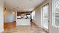 Located at 1701 Central Ave. in St. Petersburg, FL, this well-designed 2-bedroom, 3-bathroom residence offers a functional single-floor layout with contemporary finishes throughout. The open-concept kitchen and living area serves as the heart of the home, featuring light wood-look luxury vinyl flooring, a large central island with a white quartz countertop and undermount sink, dark wood cabinetry extending to the ceiling, stainless steel appliances, and stylish pendant lighting. A geometric tile backsplash and track lighting add modern character to the space. Large windows fitted with horizontal blinds flood the living area with natural light and offer views of surrounding greenery. Both bedrooms are carpeted for comfort, each equipped with a ceiling fan and windows providing natural light and outdoor views. The primary bedroom connects to a well-appointed en-suite bathroom featuring a dual-sink vanity with quartz countertops, dark cabinetry with modern hardware, and a large mirror. An additional bathroom includes a tiled tub-shower combination and wood-look flooring. A dedicated closet provides convenient storage. Neutral wall tones and clean white trim maintain a cohesive, modern aesthetic throughout the entire residence.
