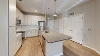 Located at 2051 Establishment Way in Charlotte, NC, this single-floor residence offers a thoughtfully designed layout with modern finishes throughout. The open-concept kitchen serves as the heart of the home, showcasing a large center island with a quartz countertop and integrated sink, pendant lighting, crisp white cabinetry with subway tile backsplash, and a full suite of stainless steel appliances including a refrigerator, range, and microwave. Wood-look flooring runs throughout the main living and kitchen areas, lending warmth and cohesion to the space. The living room is bright and airy, featuring a ceiling fan, large windows that invite natural light, and direct access to an outdoor area via a glass-panel door. The bedrooms are carpeted for comfort, with ample natural light from well-positioned windows. The primary suite includes a walk-in closet with multi-tiered wire shelving and a private en-suite bathroom complete with a glass-enclosed, tile-surround walk-in shower and wood-look flooring. A secondary bathroom features a dual-sink vanity with light cabinetry, a well-lit mirror, and hardwood-style flooring. Additional bedrooms offer plush carpet and generous closet space, making this residence functional and move-in ready.