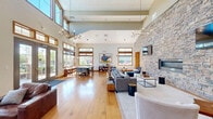Located on Riley Rd in Easton, PA, this single-story community clubhouse offers a generously sized, open layout designed for socializing and recreation. The space is unified by warm hardwood flooring and soaring vaulted ceilings that create an airy, expansive atmosphere throughout.

A dramatic full-height stacked stone accent wall serves as the architectural centerpiece, anchoring the main living area where dual wall-mounted televisions, a linear fireplace, and a chandelier create an inviting lounge environment. Comfortable seating arrangements, a curated bookshelf, and tasteful décor complete this gathering space.

The game room is a standout feature, equipped with a full-size billiards table, a ping-pong table, and pendant lighting, all set against the continued backdrop of the stone wall. High transom windows flood the space with natural light while offering views of the surrounding outdoor area.

Two dining areas provide flexible seating options, one featuring a long communal table beside large windows overlooking a pool courtyard, and another with a round café-style table nestled near the stone wall. The welcoming entrance is defined by floor-to-ceiling glass French doors that frame outdoor views and draw in abundant natural light, completing this well-appointed and versatile community space.