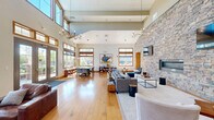 Located on Riley Rd in Easton, PA, this single-story community clubhouse offers a generously sized, open layout designed for socializing and recreation. The space is unified by warm hardwood flooring and soaring vaulted ceilings that create an airy, expansive atmosphere throughout.

A dramatic full-height stacked stone accent wall serves as the architectural centerpiece, anchoring the main living area where dual wall-mounted televisions, a linear fireplace, and a chandelier create an inviting lounge environment. Comfortable seating arrangements, a curated bookshelf, and tasteful décor complete this gathering space.

The game room is a standout feature, equipped with a full-size billiards table, a ping-pong table, and pendant lighting, all set against the continued backdrop of the stone wall. High transom windows flood the space with natural light while offering views of the surrounding outdoor area.

Two dining areas provide flexible seating options, one featuring a long communal table beside large windows overlooking a pool courtyard, and another with a round café-style table nestled near the stone wall. The welcoming entrance is defined by floor-to-ceiling glass French doors that frame outdoor views and draw in abundant natural light, completing this well-appointed and versatile community space.