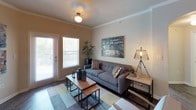 This single-floor residence offers a thoughtfully designed layout that balances comfort and functionality throughout. The living room serves as a welcoming centerpiece, featuring crown molding, rich hardwood-style flooring, and an arched architectural detail that leads toward the rest of the home. Natural light filters in through large windows, creating a warm and inviting ambiance.

The dining area, positioned near the entry, features the same dark hardwood-style flooring and recessed lighting, providing an intimate setting for gatherings. The kitchen is equipped with light maple cabinetry, granite-style countertops, tile flooring, and black appliances including a range, built-in microwave, and refrigerator. A dedicated in-unit laundry area with a full-size washer and dryer adds everyday convenience.

The primary bedroom is generously proportioned, with plush carpeting, multiple windows that invite natural light, a ceiling fan, and direct access to an outdoor area. A second bedroom offers equally comfortable accommodations with carpeted floors, a ceiling fan, and ample space that can serve a dual purpose as a bedroom and workspace.

Both bathrooms feature white cabinetry, granite-style countertops, and tile flooring. The primary bathroom includes a double-sink vanity and a tub-shower combination, while the secondary bathroom offers a single vanity and a glass-enclosed shower.