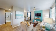 This well-designed single-story home offers two bedrooms and one bathroom across a thoughtfully arranged floor plan. The living area immediately captures attention with its bold teal accent wall, light wood-look flooring, and ceiling fan, creating a bright and welcoming atmosphere. Large-format artwork adds a coastal-inspired aesthetic that carries throughout the home. The adjoining dining area features a glass-top table set beneath a window dressed in rich navy curtains, allowing natural light to filter in while connecting seamlessly to the living space.

The kitchen is outfitted with white cabinetry, granite-look countertops, a tile backsplash, and stainless steel appliances including a refrigerator, range, and microwave. A window above the counter and a secondary entry door add both light and convenience.

The primary bedroom continues the teal accent wall theme, offering a comfortable and cohesive retreat with a ceiling fan, carpet flooring, a closet, and natural light from a window with neutral drapes. The second bedroom mirrors this design sensibility with its own window, carpet flooring, and teal accent wall.

The bathroom features a clean, tiled tub-shower combination with decorative gray tile accents. A connecting hallway ties all rooms together efficiently, completing this cohesive and thoughtfully styled home.