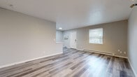 Located at 140 Meadowlands Dr in Chardon, Ohio, this two-floor residence presents a clean, modern aesthetic carried consistently throughout its interior. Light-toned luxury vinyl plank flooring runs through the main living areas and bedrooms, complementing the neutral gray walls and bright white trim that define the overall palette.

The main level features an open living area with natural light from a front-facing window, a wall-mounted A/C unit, and baseboard heating. A half-wall partition separates the living space from the kitchen area, which includes a peninsula with white quartz-style countertops. The galley-style kitchen is well-appointed with white shaker cabinetry, matching white quartz counters, a stainless steel dishwasher, electric range, over-the-range microwave, and a two-tone refrigerator. A bathroom on this level features a tub/shower combination, white vanity with undermount sink, and tile flooring.

The second floor offers additional living space with track lighting, carpeted stairs, and access to a bedroom featuring a ceiling fan, window, wall A/C unit, and a closet with sliding panel doors. A second bathroom on this level provides a vanity with white cabinetry, undermount sink, and tile flooring.