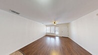 This single-floor Manhattan residence offers a practical and well-designed layout, accommodating four bedrooms, two bathrooms, a combined kitchen and living room, and a hallway. Throughout the living and sleeping areas, rich wood-look flooring provides a warm, cohesive aesthetic, complemented by clean white walls and white trim that create a bright, neutral backdrop.

The living room is a welcoming space featuring a ceiling fan with integrated lighting, large windows fitted with blinds that invite natural light, and direct access to an exterior door. The four bedrooms continue the hardwood-style flooring, and several rooms are equipped with ceiling fans. The primary bedroom is a comfortable, well-proportioned retreat with windows that provide outdoor views and natural light. Arched white panel doors are a consistent architectural detail throughout the unit.

The kitchen is thoughtfully appointed with rich wood cabinetry, light granite countertops, a double-basin sink with an oil-rubbed bronze faucet, and black appliances including a range and refrigerator. Tile flooring grounds the kitchen area distinctly from the rest of the unit.

Both bathrooms feature tub-shower combinations with full-height large-format tile surrounds in a neutral stone finish, paired with oil-rubbed bronze fixtures, lending a classic and cohesive look. The overall ambiance of the space is clean, functional, and move-in ready.