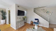 This two-story residence offers a thoughtfully arranged layout across both levels, combining functional design with welcoming interiors. The main living area greets visitors with warm hardwood-style flooring, neutral wall tones, and a light-filled atmosphere. A glass-top coffee table and open sightlines connect the living space to a dedicated dining area, creating a cohesive flow ideal for everyday living and entertaining. A staircase with white railings leads to the upper level.

The kitchen features white cabinetry, granite-toned countertops, a stainless steel dishwasher, and a black range, offering ample storage and efficient workspace. Two bathrooms serve the residence — one with a wide vanity, beige countertop, and decorative mirror, and another with a full soaking tub, white cabinetry, and hardwood-style flooring throughout.

The bedrooms each carry distinct character. One features a bold, artistic accent wall mural with a crystal pendant light and walk-in closet, while another presents a softer palette with natural light filtering through patterned drapes. Carpeted floors in the bedrooms add comfort underfoot. Textured ceilings are consistent throughout, and the overall aesthetic maintains a cohesive, modern residential feel across both floors.