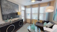 This 1-bedroom, 1-bathroom unit delivers a thoughtfully designed single-story layout that maximizes both comfort and functionality. The living room is bright and welcoming, featuring multiple large windows with blinds and floor-length curtains that allow generous natural light to fill the space. A ceiling fan overhead and wood-style flooring throughout contribute to a cohesive, modern aesthetic.

The kitchen is well-appointed with dark cabinetry, granite countertops, black appliances including a gas range, microwave, and refrigerator, and track lighting overhead. A peninsula with pendant lighting and seating provides an ideal space for dining or casual gathering, seamlessly connecting the kitchen to the living area.

The bedroom is generously sized, accommodating a large bed with ease, and includes a ceiling fan, wood-style flooring, and a wide window with outdoor views. Ample storage is offered through closet space accessible from the room.

The bathroom features a granite-topped vanity with dark cabinetry, tile flooring, and a full soaking tub and shower combination. An adjacent walk-in closet adds practical storage. A dedicated in-unit laundry area with a full-size washer and dryer is conveniently located nearby, rounding out the practical amenities of this well-configured home.