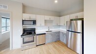This contemporary 740 square foot apartment offers a harmonious blend of modern design and practical living. The space features two bedrooms, including a primary bedroom of 170 square feet, and one bathroom. The open-concept layout creates a sense of spaciousness, enhanced by large windows that flood the rooms with natural light and provide scenic outdoor views.

The kitchen is a standout feature, boasting sleek stainless steel appliances, ample cabinet space with a mix of white and wood-grain finishes, and a stylish backsplash. The industrial-chic aesthetic is accentuated by exposed ductwork running along the ceilings, adding character to the space.

Flooring throughout the apartment varies, with warm wood-look flooring in the kitchen and living areas, and plush carpeting in the bedrooms for added comfort. The bathroom combines functionality with style, featuring a full-sized tub and modern fixtures.

Storage is well-considered, with two closets to keep belongings organized. The apartment's neutral color palette provides a blank canvas for personalization, while the large windows and high ceilings contribute to an airy, expansive feel. Located in Saint Paul, MN, this apartment offers urban convenience with a touch of contemporary flair.