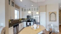 Located at 260 Leigh Farm Rd in Durham, NC, this thoughtfully designed single-floor residence offers a cohesive blend of modern finishes and comfortable living spaces throughout. The kitchen is a standout feature, showcasing white shaker cabinetry that extends to the ceiling with glass-front upper cabinets, a mosaic tile backsplash, dark granite countertops, and a full suite of stainless steel appliances. A center island with a granite top and pendant lighting above adds both function and style, while recessed lighting and a natural light source from a nearby window brighten the space. The dining area is positioned adjacent to the kitchen and features warm hardwood flooring, large windows, and a glass door providing access to an outdoor balcony, creating an inviting atmosphere for meals. The living area offers expansive triple windows that frame outdoor views and fill the room with natural light. The bedrooms are generously proportioned, featuring plush carpeting, large windows with abundant natural light, and ceiling fans for comfort. A well-appointed bathroom connects to the bedroom suite, featuring a white vanity with dark countertops, a framed mirror, and tile flooring. The in-unit laundry room provides added convenience with side-by-side washer and dryer units. Neutral warm tones and consistent finishes throughout lend the home a polished, move-in-ready appeal.