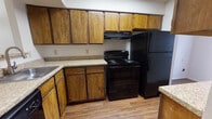 Located at 8301 N Council Rd in Oklahoma City, Oklahoma, this two-floor residential space offers a practical and comfortable layout with several notable features throughout. The kitchen is well-equipped with warm-toned wood cabinetry extending to the ceiling, granite-style countertops, wood-look flooring, and black appliances including a range, refrigerator, and dishwasher. A double sink and ample counter space make the kitchen highly functional. The kitchen opens toward the living area via a partial wall, providing a connected feel between the spaces. The spacious living room is carpeted and features a standout stone-surround fireplace, a ceiling fan with light fixture, a textured ceiling, and a window that allows natural light to fill the room. The bedrooms are carpeted and bright, each equipped with ceiling fans, windows with blinds, and walk-in closets offering generous storage. The bathrooms feature wood-look flooring, wood vanities with granite-style countertops, framed mirrors, and tiled shower-tub combinations. A half bath is also present, providing added convenience. Throughout the space, neutral tones and consistent finishes create a cohesive and livable atmosphere across both floors.