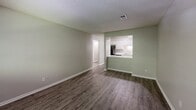 Located at 1912 Heathcliff Dr in Dalton, GA, this single-floor, one-bedroom, one-bathroom unit offers a practical and well-organized layout. The living room is finished with durable hardwood-style flooring and neutral sage-green walls, creating a clean, open feel. A pass-through opening connects the living area directly to the kitchen, enhancing the sense of openness throughout. The kitchen is efficiently designed with white cabinetry lining both sides of a galley-style corridor, light stone countertops, a stainless steel sink, and a full suite of black appliances including a refrigerator, electric range, and dishwasher. A textured ceiling runs throughout the unit. The bedroom features soft carpeting, sage-toned walls, and a window overlooking surrounding greenery, providing natural light and a quiet atmosphere. A dedicated closet offers convenient storage. The bathroom is appointed with a full tiled shower-tub combo, brushed nickel fixtures, and wood-style flooring. A hallway connects the main living spaces, adding to the unit's efficient flow. Overall, this space delivers a clean, functional living environment with consistent finishes throughout.