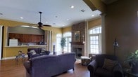 Located at 1733 Pops Ferry Rd in Biloxi, Mississippi, this single-story home offers a comfortable and well-appointed living environment. The main living area serves as the heart of the home, showcasing a classic brick fireplace flanked by decorative columns that add architectural character to the space. A framed mirror above the mantle enhances the focal point, while recessed lighting and a ceiling fan provide both ambiance and practical comfort throughout the room.

Large arched windows along multiple walls flood the living area with natural light, offering bright, open views to the outdoors. The warm-toned walls complement the rich hardwood-style flooring, creating an inviting atmosphere. The open layout connects the living room to the kitchen, which features wood cabinetry and appears well-equipped for daily use.

The space is thoughtfully designed with an emphasis on flow and functionality, with generous room to accommodate comfortable seating arrangements. The combination of traditional architectural details—arched windows, decorative columns, and a brick fireplace surround—gives the home a classic Southern charm that is both welcoming and timeless.