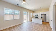 This thoughtfully designed single-floor residence offers a cohesive and modern living experience across its efficiently arranged layout. The open-concept kitchen and living room serves as the heart of the home, featuring light hardwood-style flooring, neutral warm-toned walls, and abundant natural light streaming through multiple windows and sliding glass doors that lead to an outdoor area. A ceiling fan overhead enhances airflow and comfort throughout the shared living space.

The kitchen is a standout feature, boasting crisp white shaker-style cabinetry, granite countertops, a central island with an undermount stainless steel sink, and a full suite of stainless steel appliances including a refrigerator with ice maker, electric range, microwave, and dishwasher. Elegant pendant lighting above the island adds a polished finishing touch.

The bedroom is a comfortable, well-proportioned retreat with multiple windows that invite natural light and a ceiling fan for added comfort. The bathroom is finished with a white vanity, granite countertop, undermount sink, and a large mirror, maintaining the clean, contemporary aesthetic found throughout the home. A hallway connects the rooms seamlessly, and a dedicated entrance provides a welcoming transition into the space. The outdoor area features a patio and greenery, extending the living experience beyond the interior.