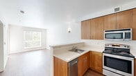 This one-bedroom, one-bathroom apartment at 1250 E Burnside St in Portland's vibrant Lower Buckman neighborhood offers a well-designed layout across a single floor. The open-concept living area features warm hardwood-style flooring and large windows fitted with blinds, allowing abundant natural light to filter in alongside views of surrounding greenery. A glass door opens directly onto a private balcony, extending the living space outdoors.

The kitchen is thoughtfully appointed with warm wood cabinetry, light countertops, and a full suite of stainless steel appliances including a refrigerator, range, built-in microwave, and dishwasher. A peninsula separates the kitchen from the living area, creating a practical and social flow between spaces.

The bedroom offers plush carpeting underfoot, a window with tree-lined views, and a set of sliding double-door closets providing ample storage. The bathroom complements the unit's modern aesthetic with matching wood-toned cabinetry, a large vanity mirror, light countertops, and a shower-tub combination, all set on hardwood-style flooring.

Clean white walls throughout lend the space a bright, neutral backdrop, making it easy to personalize. The unit combines functional design with comfortable details in a well-connected Portland location.
