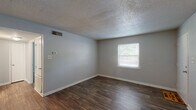 Located at 301 W Vandalia Rd in Greensboro, NC, this single-story home offers a practical and well-organized layout across four bedrooms, one full bathroom, a kitchen, and a connecting hallway. Throughout the home, dark hardwood-style flooring provides a cohesive look, complemented by neutral gray walls and textured ceilings.

The kitchen is efficiently designed with white shaker-style cabinetry extending to the ceiling for ample storage, light countertops, and a full suite of stainless steel appliances including a range, dishwasher, and refrigerator. A built-in shelving nook adds additional storage character.

Each bedroom features the same dark flooring and neutral palette, with windows fitted with blinds that allow natural light and outdoor views of the surrounding greenery. The primary bedroom offers a comfortable footprint with closet access. Additional bedrooms include closets with double doors and direct hallway connectivity.

The full bathroom is bright and clean, finished in all-white with a tub-shower combination, a vanity with under-sink storage, and wood-look tile flooring. A dedicated utility closet houses the water heater and includes overhead shelving. The home's straightforward layout and consistent finishes make it a functional and move-in-ready residence.