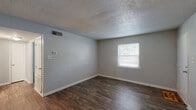 Located at 301 W Vandalia Rd in Greensboro, NC, this single-story home offers a practical and well-organized layout across four bedrooms, one full bathroom, a kitchen, and a connecting hallway. Throughout the home, dark hardwood-style flooring provides a cohesive look, complemented by neutral gray walls and textured ceilings.

The kitchen is efficiently designed with white shaker-style cabinetry extending to the ceiling for ample storage, light countertops, and a full suite of stainless steel appliances including a range, dishwasher, and refrigerator. A built-in shelving nook adds additional storage character.

Each bedroom features the same dark flooring and neutral palette, with windows fitted with blinds that allow natural light and outdoor views of the surrounding greenery. The primary bedroom offers a comfortable footprint with closet access. Additional bedrooms include closets with double doors and direct hallway connectivity.

The full bathroom is bright and clean, finished in all-white with a tub-shower combination, a vanity with under-sink storage, and wood-look tile flooring. A dedicated utility closet houses the water heater and includes overhead shelving. The home's straightforward layout and consistent finishes make it a functional and move-in-ready residence.