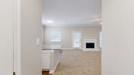 This single-story, 3-bedroom, 2-bathroom home offers a thoughtfully designed layout that maximizes comfort and functionality. The open-concept kitchen and living room serve as the heart of the home, seamlessly connected for everyday living and entertaining. The kitchen is well-equipped with white cabinetry, stainless steel appliances, a gray subway tile backsplash, and a granite-topped peninsula with an undermount sink — providing ample workspace and a natural gathering point. Wood-look flooring anchors the kitchen area, while the living room transitions to plush carpeting underfoot. Crown molding frames the living room ceiling, which is accented by a ceiling fan and filled with natural light from multiple windows with blinds. A white-mantled fireplace with tile surround serves as a standout focal point. The primary bedroom offers generous proportions, carpeted floors, a ceiling fan, a double-door closet, and direct access to an en-suite bathroom featuring a granite vanity, white cabinetry, and a tub-shower combination. The additional bedrooms are well-sized with carpeted floors, ceiling fans, and natural light. The bathrooms maintain a clean, consistent aesthetic with granite countertops and wood-look flooring. A dedicated hallway and entrance complete the practical floor plan of this comfortable home.