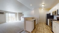 This single-floor unit at 2201 E Forest St in Marshfield, Wisconsin, offers a well-designed, open-concept layout finished with a consistent neutral palette throughout. The kitchen is outfitted with white cabinetry, granite-look countertops, light wood-style vinyl flooring, and stainless steel appliances, including a range, microwave, refrigerator, and dishwasher. A peninsula counter connects the kitchen to the open living area, which features plush wall-to-wall carpeting and a window that allows natural light to fill the space.

The unit includes two bathrooms: one with a walk-in shower, white cabinetry, and granite-look countertops, and a second featuring a tub-shower combination with similar finishes. Both bathrooms carry the same light wood-style flooring found in the kitchen and common areas.

The bedrooms are carpeted and generously sized, with large windows offering outdoor views. At least one bedroom includes a walk-in closet with built-in shelving, providing practical storage. A dedicated laundry room houses a full-sized washer and dryer alongside wire shelving for additional storage. The overall design is clean, functional, and move-in ready.